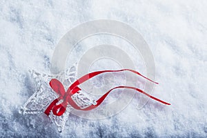 Beautiful magical vintage white star tied with a red ribbon on a white snow background. Winter and Christmas concept.