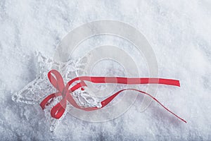 Beautiful magical vintage white star tied with a red ribbon on a white snow background. Winter and Christmas concept.