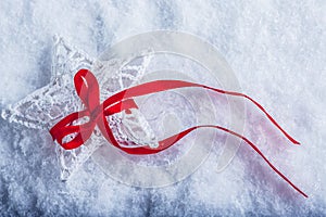 Beautiful magical vintage white star tied with a red ribbon on a white snow background.