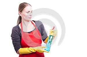 Beautiful maid in workwear looking at cleaning spray