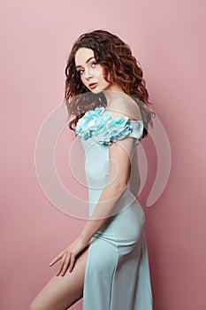 Beautiful makeup of sexy woman in turquoise dress on pink background. Slim perfect figure body girl, bright makeup, facial skin