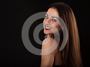 Beautiful makeup toothy smiling woman with long hair looking happy on black background. Closeup portrait of natural happiness