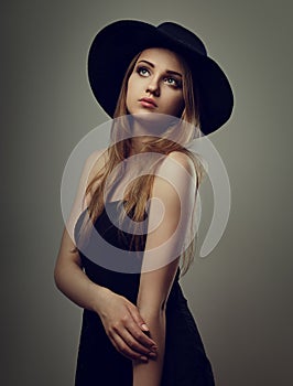 Beautiful makeup woman with long blond hair style in black hat on studio background.. Closeup glamor portrait. vintage toned color