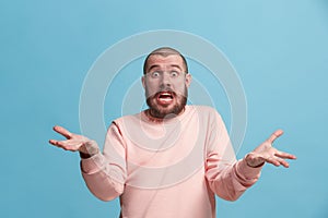 Beautiful male half-length portrait isolated on blue studio backgroud. The young emotional surprised man