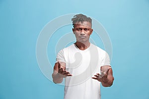 Beautiful male half-length portrait isolated on blue studio backgroud. The young emotional surprised man