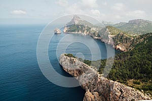 Beautiful Mallorca rocky coast covered with green forest. Balearic Sea as a part of Mediterranean Sea washing Es Colomer cape