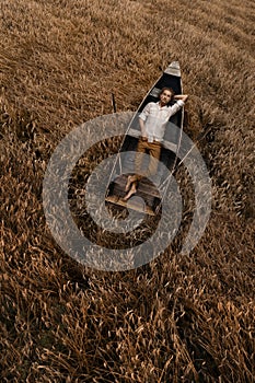 Beautiful man laying at the boat in the field of wheat
