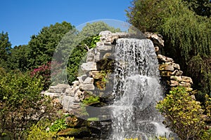 Beautiful man-made waterfall among rocks and trees