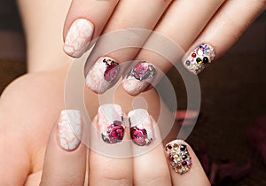 Beautiful manicure with flowers on female fingers. Nails design. Close-up