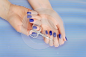 Beautiful manicure process. Nail polish being applied to hand, polish is a blue color.