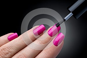 Beautiful manicure process. Nail polish being applied to hand, polish is a pink color.