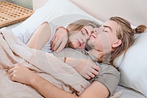 Beautiful married couple lies hugging in bed, life together, relationship in a pair