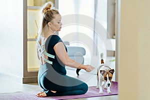 Beautiful mature body positive lady leading healthy lifestyle doing yoga whilst caring for furry friend.