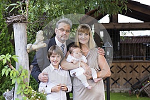 Beautiful mature couple in formal dress and suit with two kids in a garden