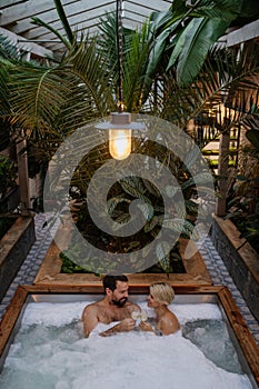 Beautiful mature couple relaxing in hot tub, drinking champagne, enjoying romantic wellness weekend in spa. Concept