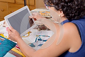 Beautiful mature seamstress using tablet computer