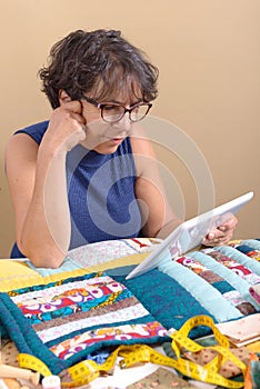 Beautiful mature seamstress using tablet computer
