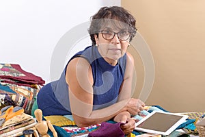 Beautiful mature seamstress using tablet computer