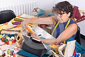 Beautiful mature seamstress using tablet computer