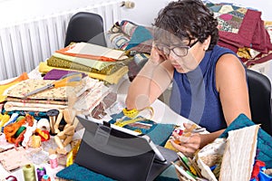 Beautiful mature seamstress using tablet computer
