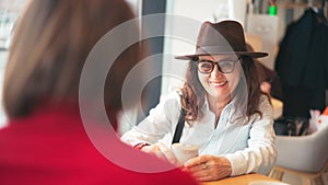 A beautiful mature stylish woman in a hat and glasses talking with her daughter