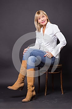 Beautiful mature woman 40s sitting in chair studio