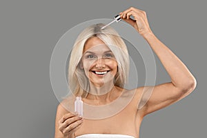 Beautiful Mature Woman Applying Hair Serum With Droplet