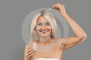 Beautiful Mature Woman Applying Hair Serum With Droplet photo