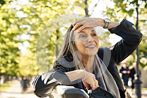 Beautiful mature woman in autumn park flooded with sunlight