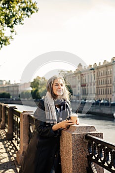 Beautiful mature woman in  autumn park near  embankment