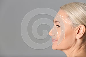 Beautiful mature woman after facelift cosmetic surgery procedure on grey background. Space for text photo