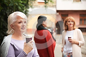 Beautiful mature woman and her friends drinking coffee outdoors