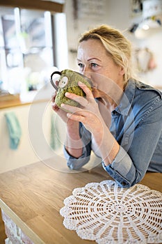 Beautiful mature woman at home, drinking hot tea at morning. Older woman living alone, enjoying peaceful weekend day