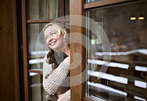 Beautiful mature woman at home, holding, petting her cat, looking from window. Older woman living alone, enjoying