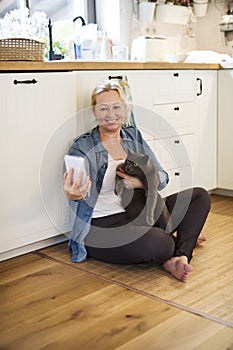 Beautiful mature woman at home, taking selfie with her cat. Older woman living alone, enjoying peaceful weekend day