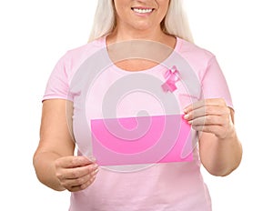 Beautiful mature woman with pink ribbon holding card on white background. Breast cancer concept