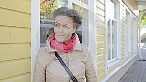 Beautiful mature woman thinking against yellow wooden house