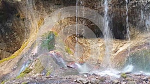 Beautiful meager streams of water karst waterfall. Green moss grows on slippery wet stones. Caucasian nature