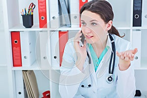 Beautiful medical doctor talking on the phone with patient.