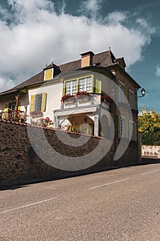 Beautiful medieval house with stone fence, garden and street lamp. Nice village street in France. Residential cottage with flowers