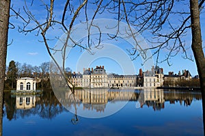 Beautiful Medieval landmark - royal hunting castle Fontainbleau with reflection in water of pond.