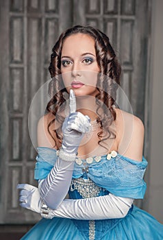 Beautiful medieval woman in blue dress making silence gesture