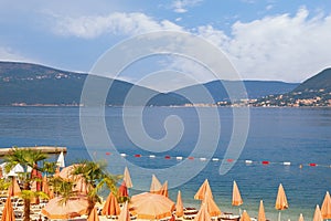 Beautiful Mediterranean landscape with beach umbrellas. Summer beach vacation. Montenegro. View of Bay of Kotor