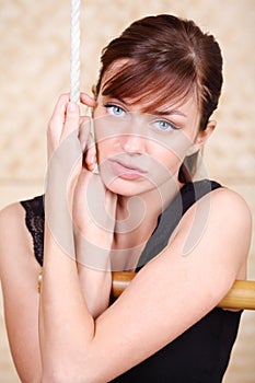 Beautiful melancholy woman holds on bamboo rope ladder.