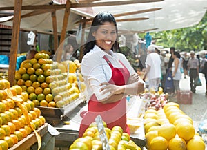 Beautiful mexican saleswoman with oranges on a farmers market