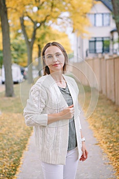 Beautiful middle age Caucasian woman with short hair walking in autumn fall street outdoors. Young woman with short haircut in