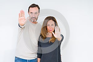 Beautiful middle age couple in love over isolated background doing stop sing with palm of the hand