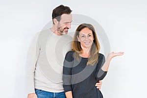 Beautiful middle age couple in love over isolated background smiling cheerful presenting and pointing with palm of hand looking at