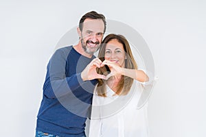 Beautiful middle age couple in love over isolated background smiling in love showing heart symbol and shape with hands