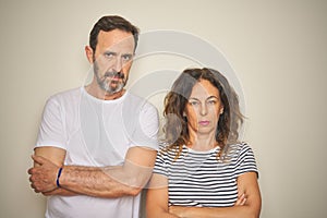 Beautiful middle age couple together standing over isolated white background skeptic and nervous, disapproving expression on face